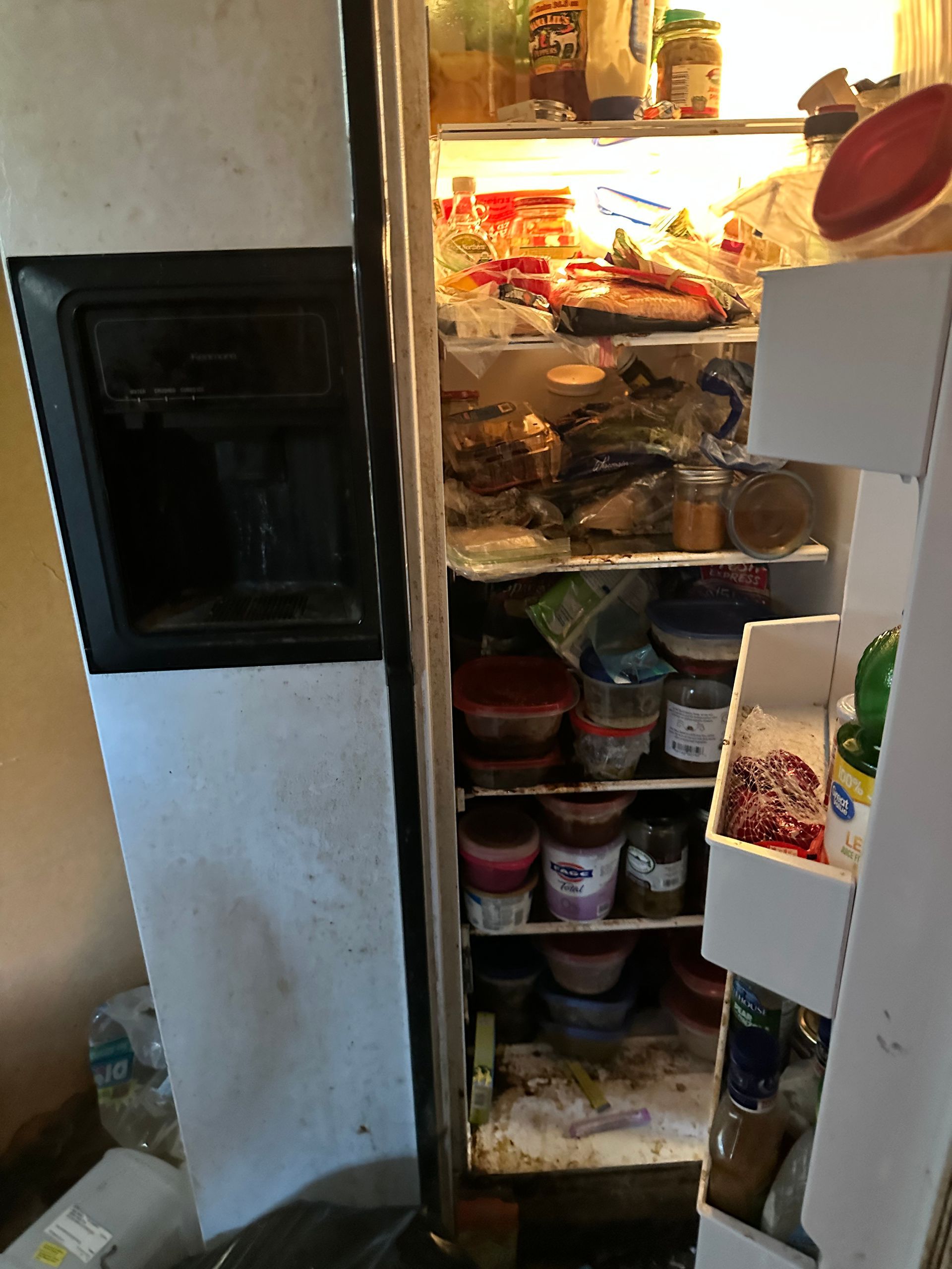 Open refrigerator filled with food. White appliance with dispenser.