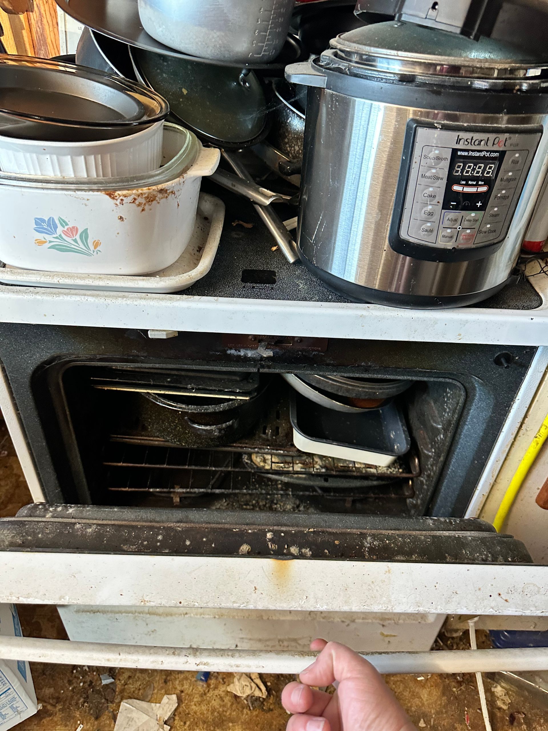 Dirty oven open with dishes inside; stovetop covered in pots and an Instant Pot.