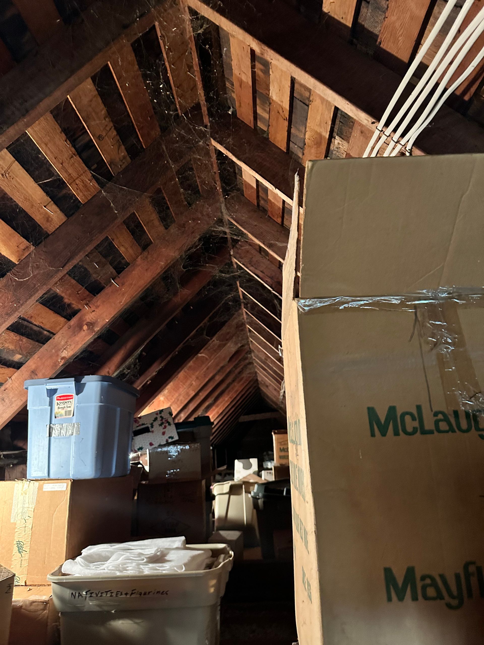 Attic interior with exposed wooden beams, boxes and storage containers.