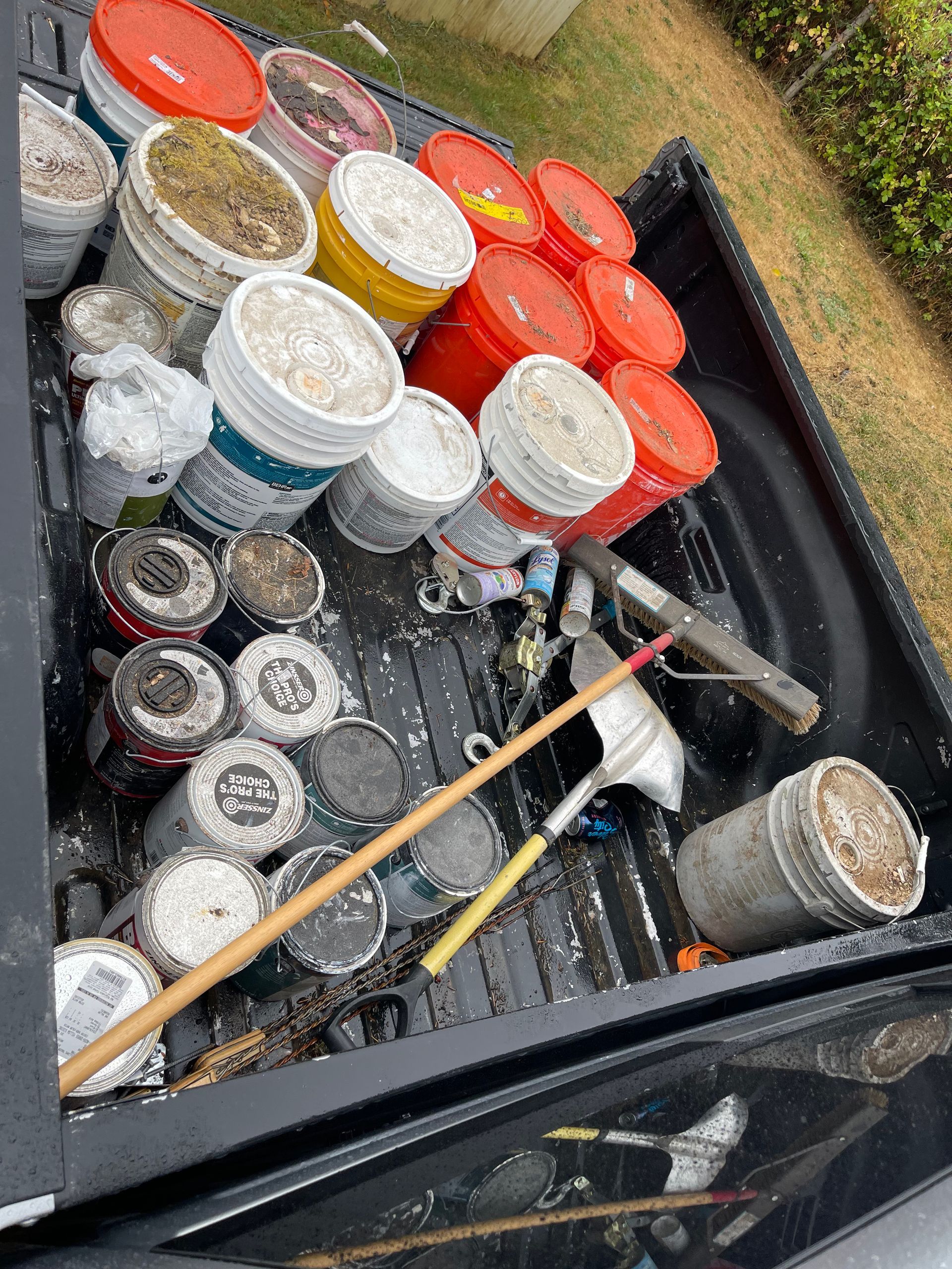 Truck bed filled with used paint cans, tools, and debris; various colors and textures visible.