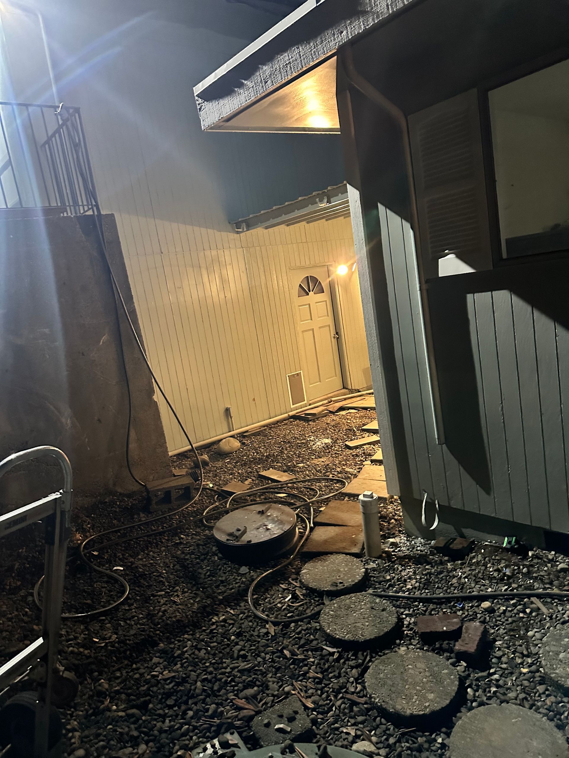 Charred debris in an outdoor area. Damaged building with open door, visible interior.