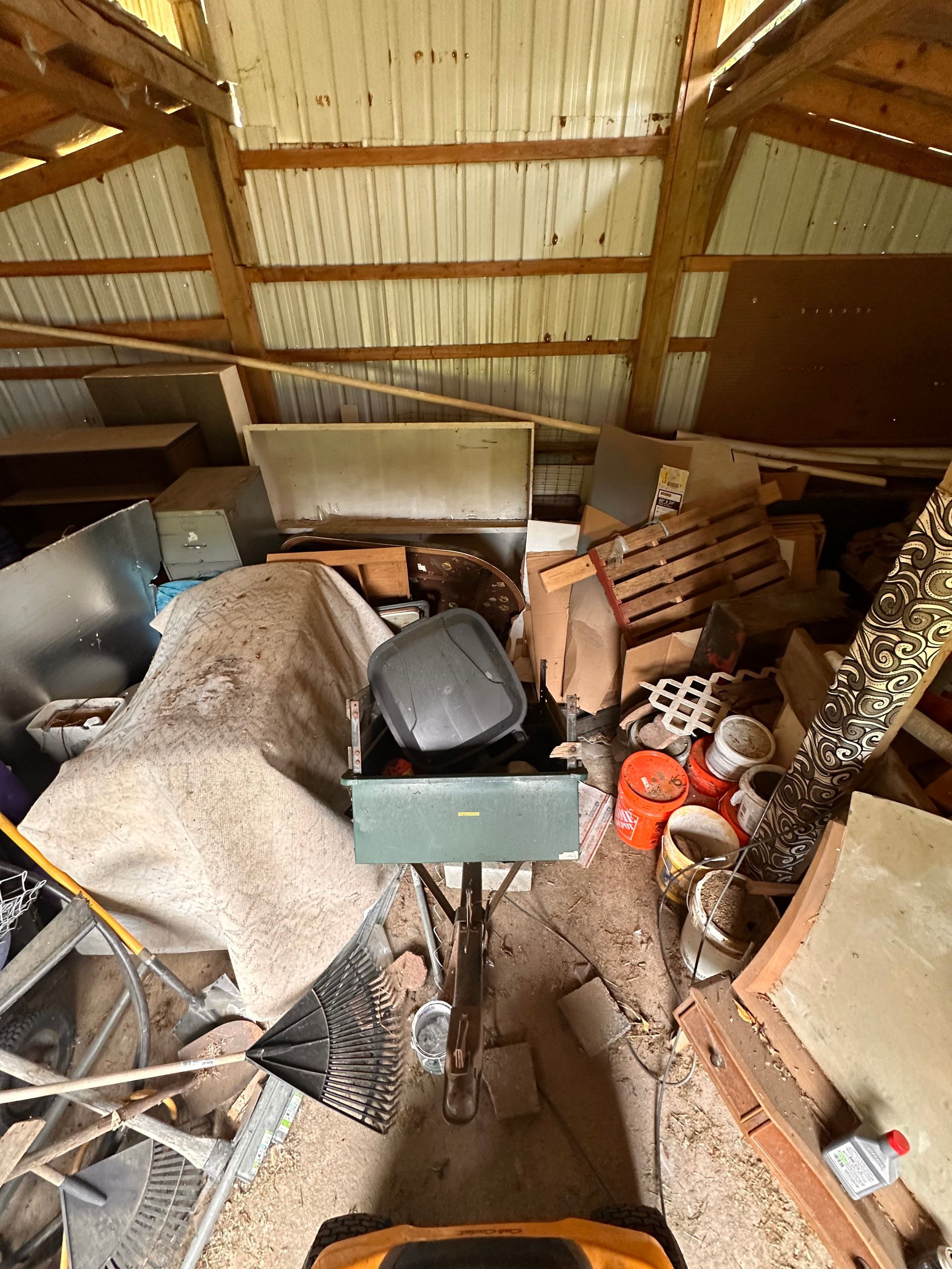 Overhead view inside a cluttered shed with a wheelbarrow in the center.