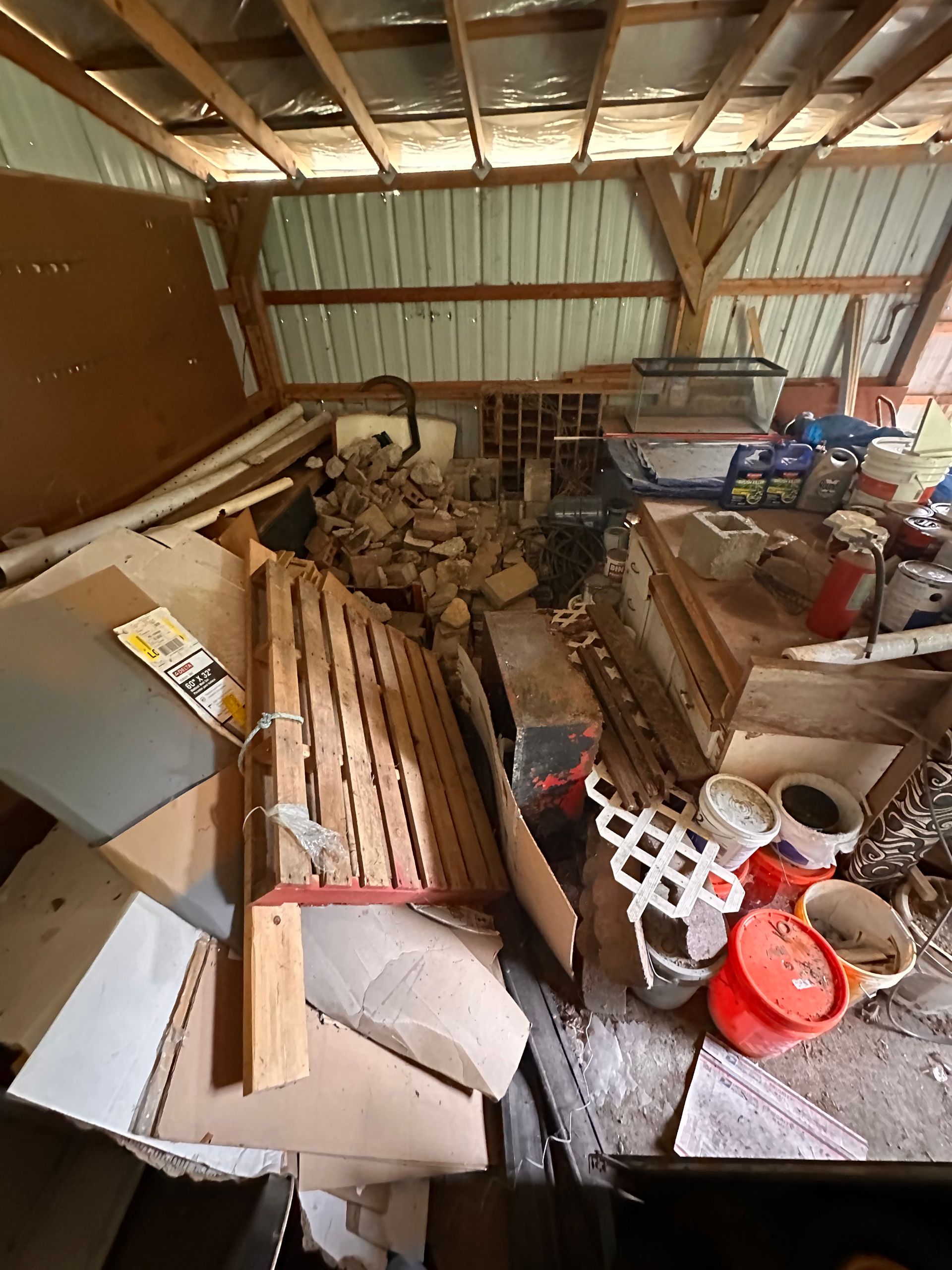 Cluttered barn interior with debris, wooden beams, and various objects.
