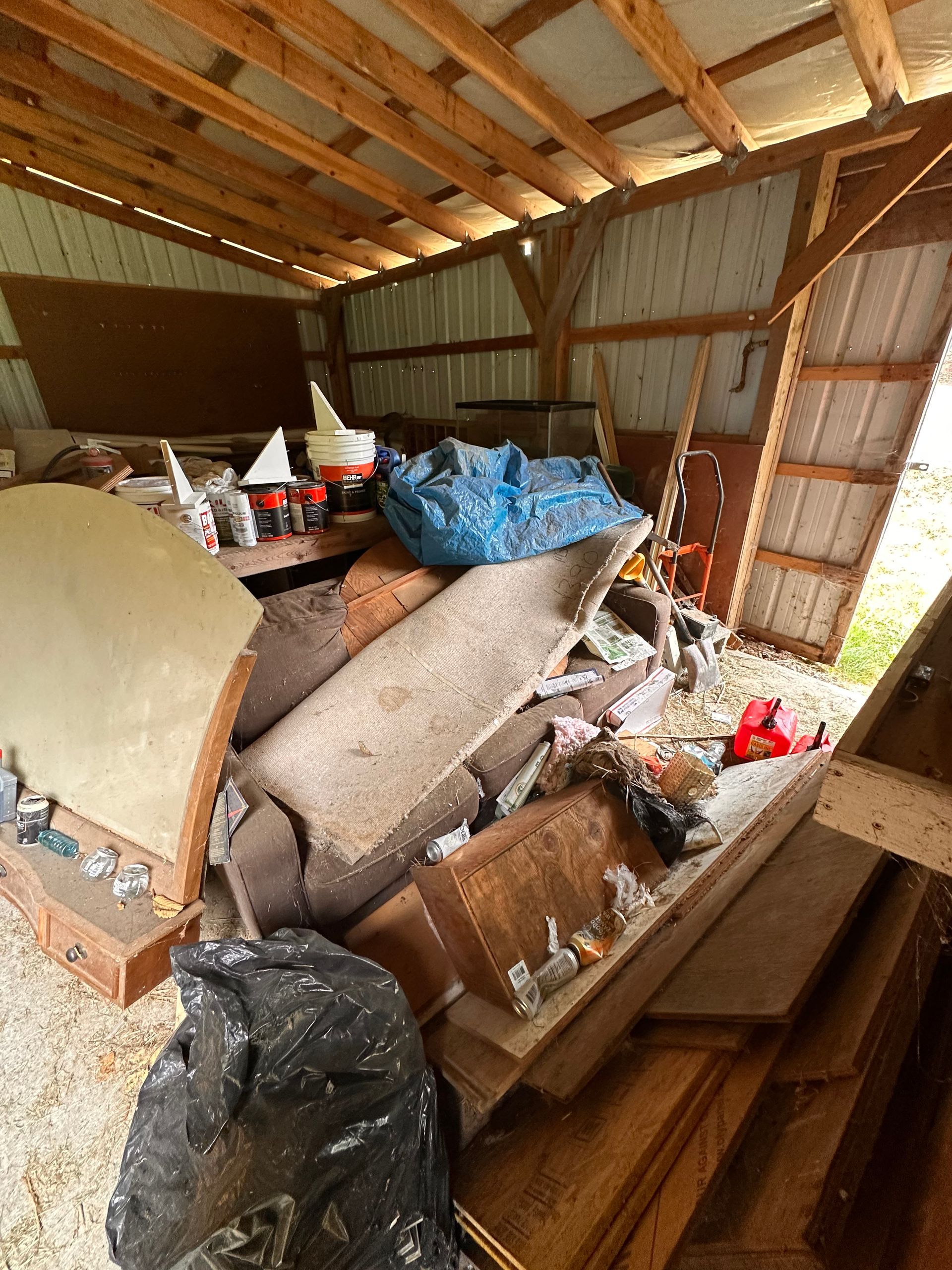 Messy shed interior filled with debris, wood, and a blue tarp.
