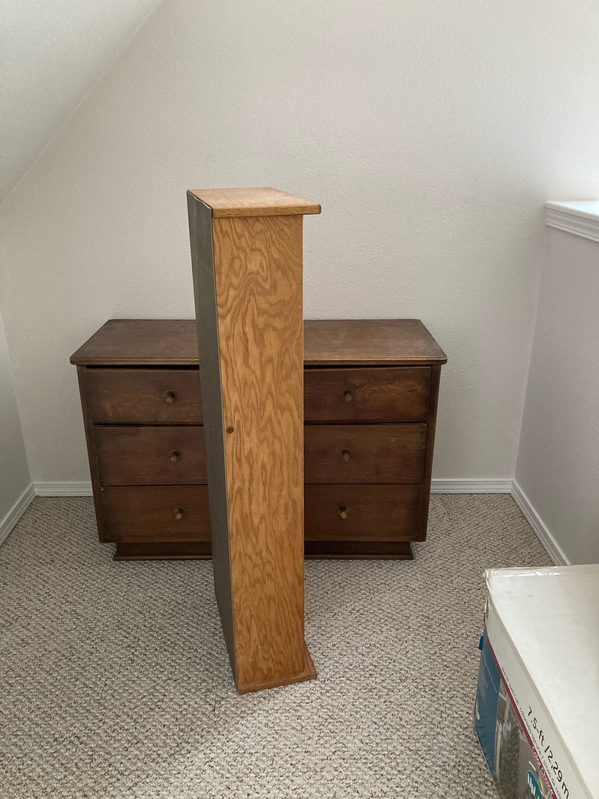 Wooden cabinet and dresser in a carpeted room. The cabinet is vertical, and the dresser has three drawers.