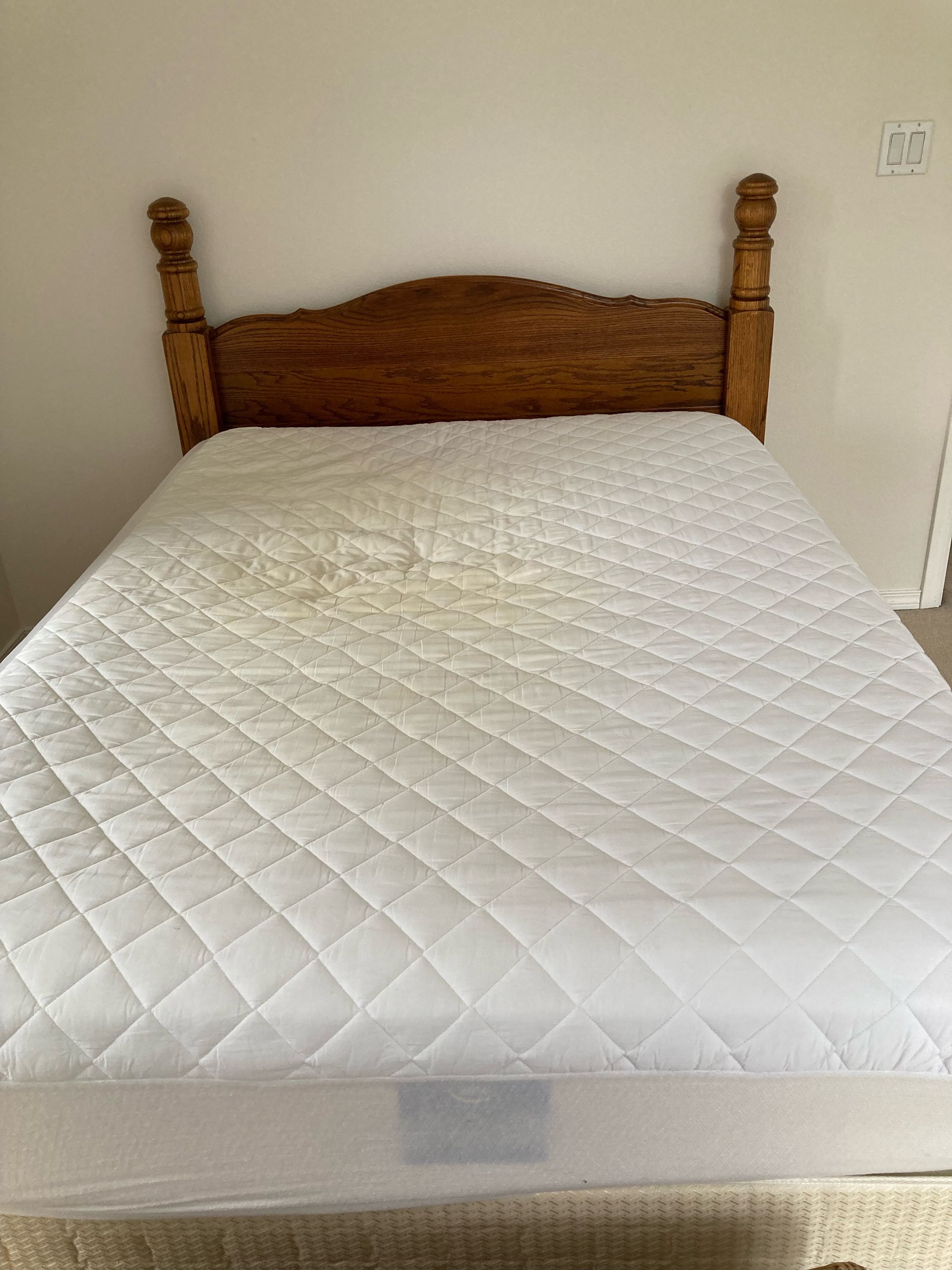Wooden bed frame with a white quilted mattress.