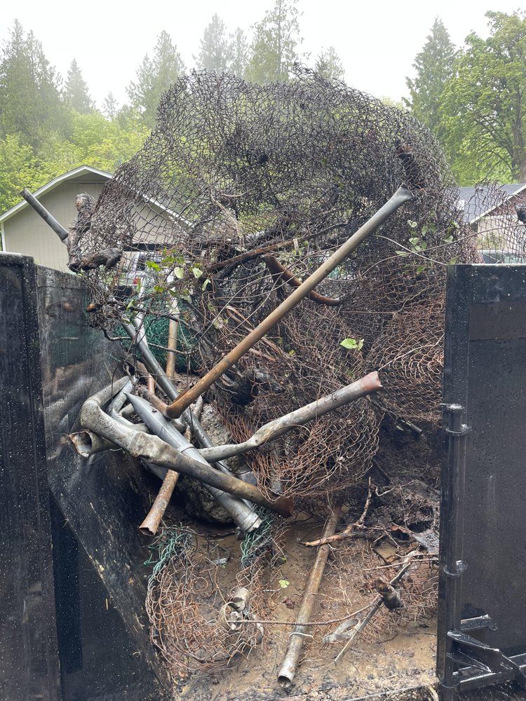 Debris and netting overflowing from a dark container. Metal rods and vegetation visible.