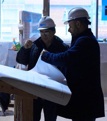 Two men wearing hard hats are looking at a blueprint