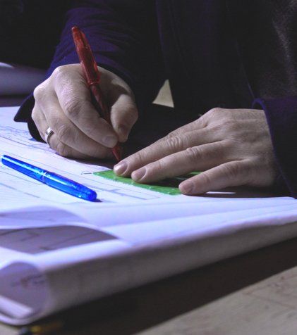 A person is writing on a piece of paper with a red pen