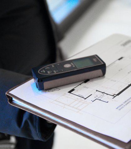 A person is holding a blueprint and a tape measure