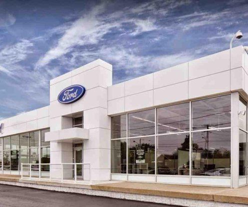 A large white ford dealership with a lot of windows.