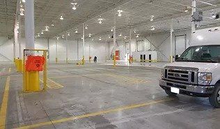 A white van is parked in an empty warehouse.