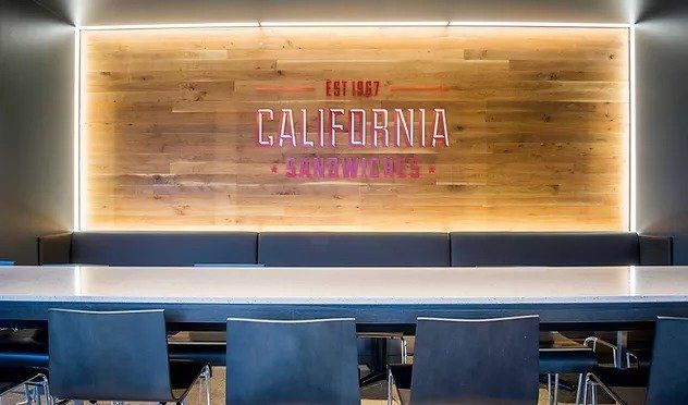 A long table with chairs in front of a wooden wall with the word california on it.