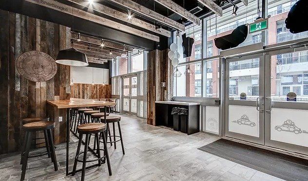 A large room with a table and stools in it.