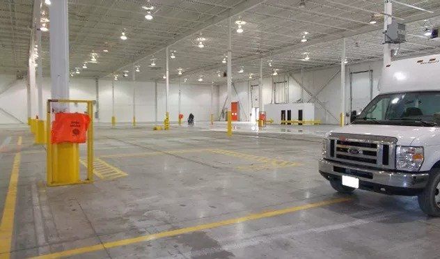 A white van is parked in an empty warehouse.