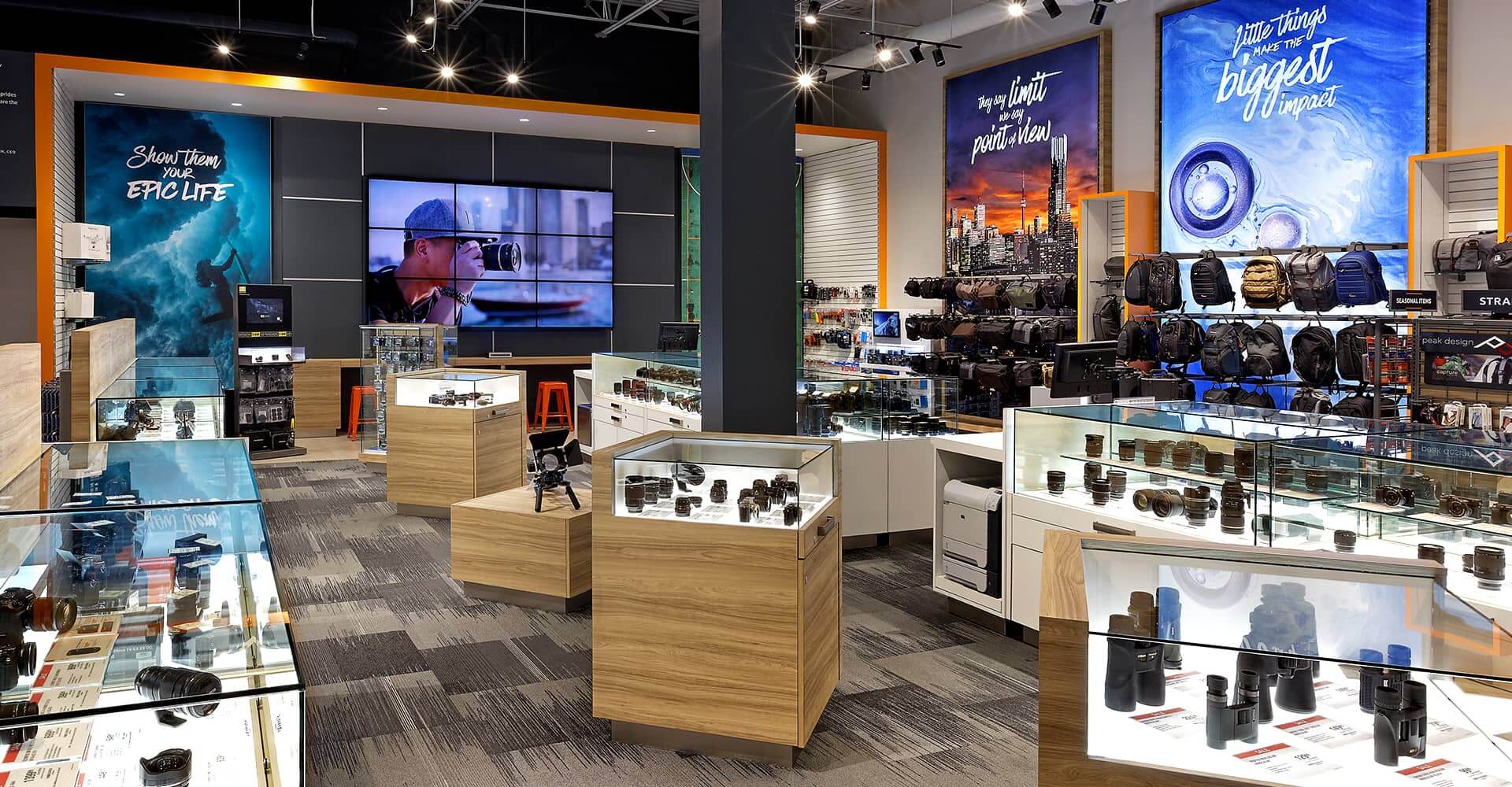 A camera store filled with lots of cameras and a large screen.