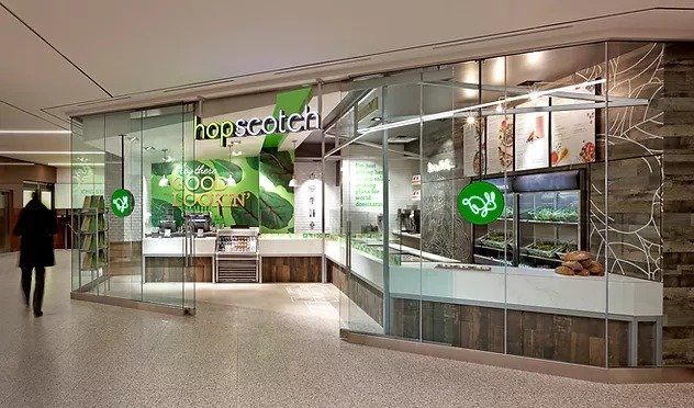 A person is walking in front of a restaurant with a glass door.