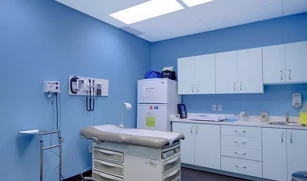 A doctor 's office with blue walls and white cabinets.