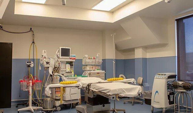 An empty operating room in a hospital with a bed and a monitor.