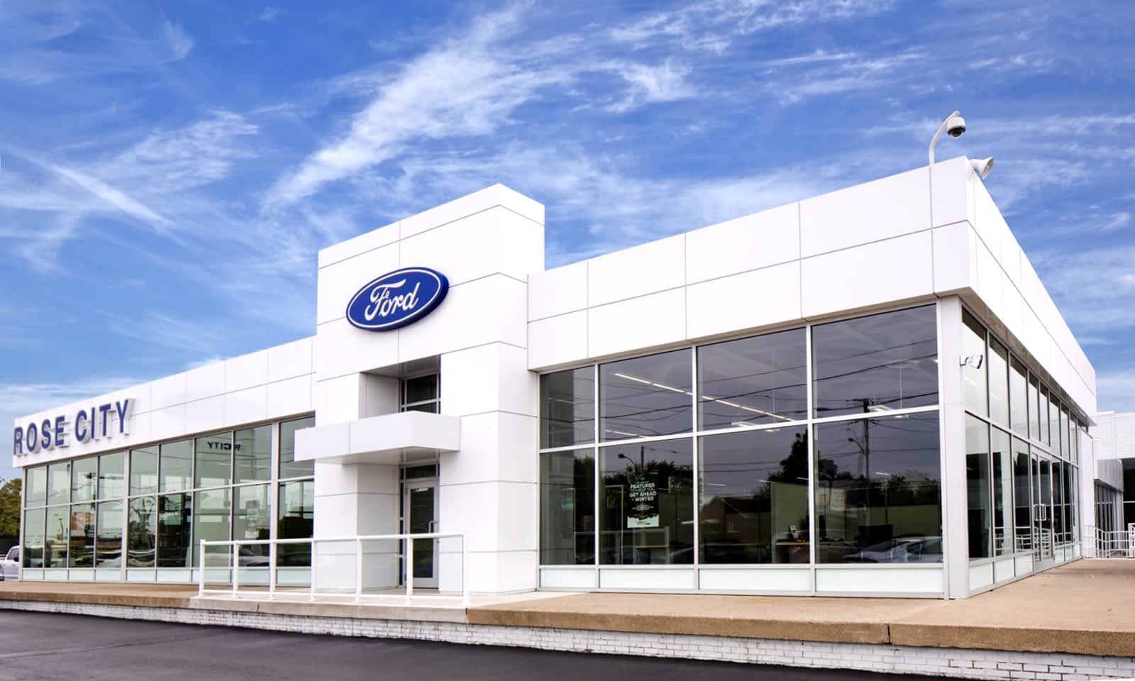 A large white ford dealership with a lot of windows