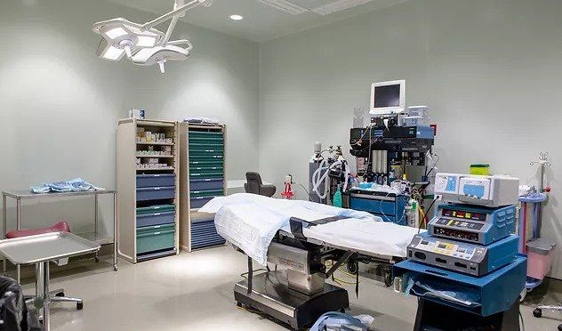 An empty operating room in a hospital with a bed and a monitor.