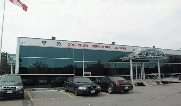 Cars are parked in front of a building that says collision reporting centre