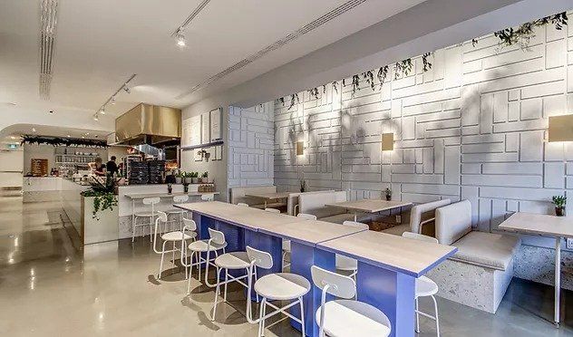 A restaurant with tables and chairs and a white brick wall.