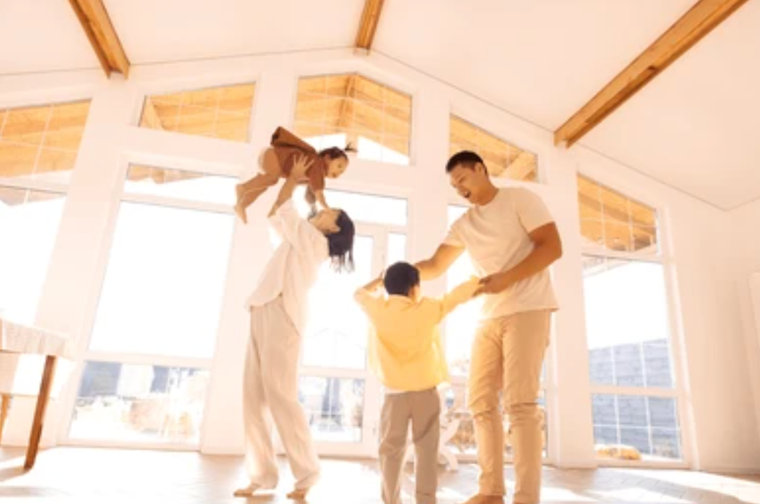 A family is playing in a living room with a lot of windows.
