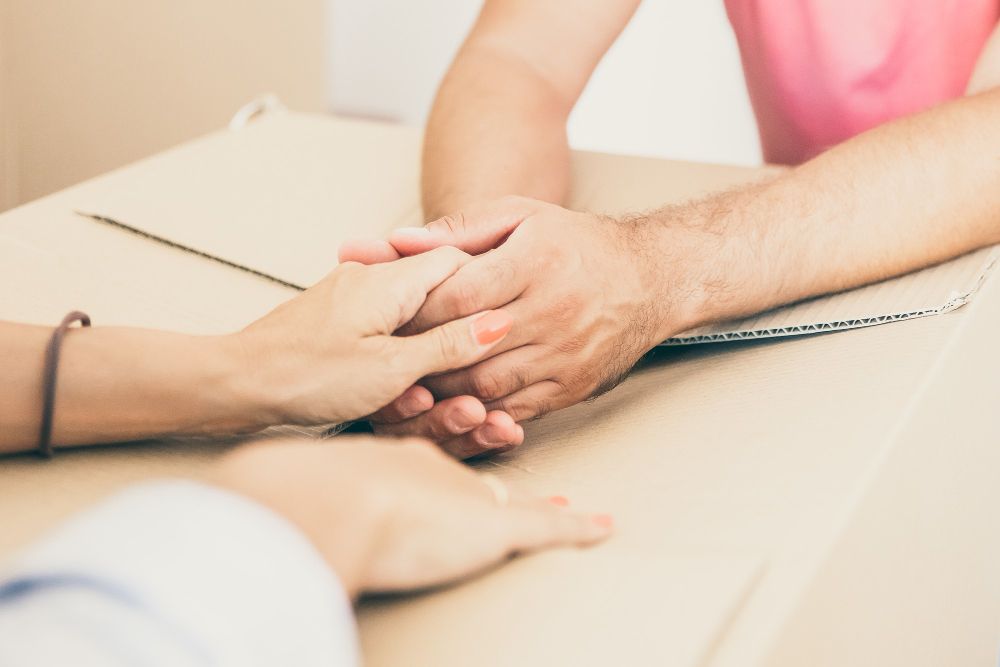 A woman is holding a man 's hand while sitting at a table.