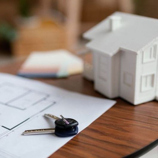A model house and keys are on a wooden table.