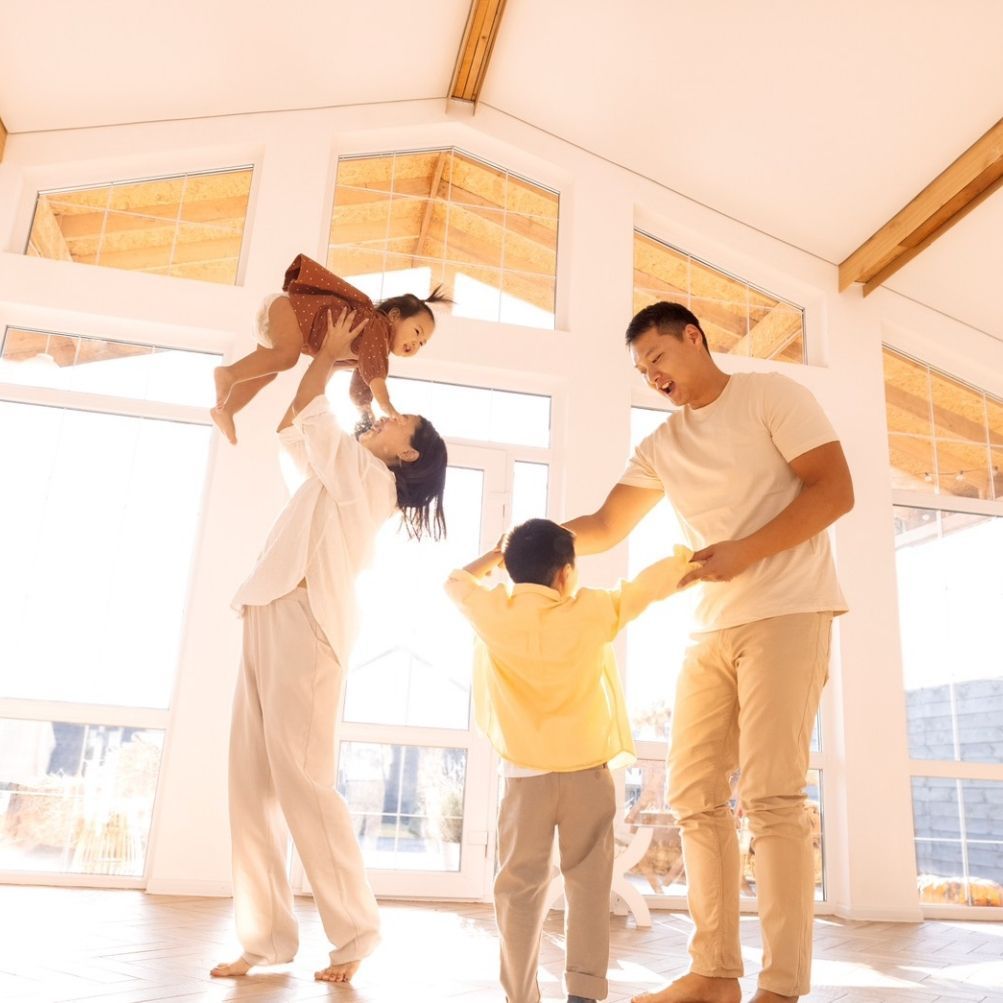 A family is playing in a room with lots of windows