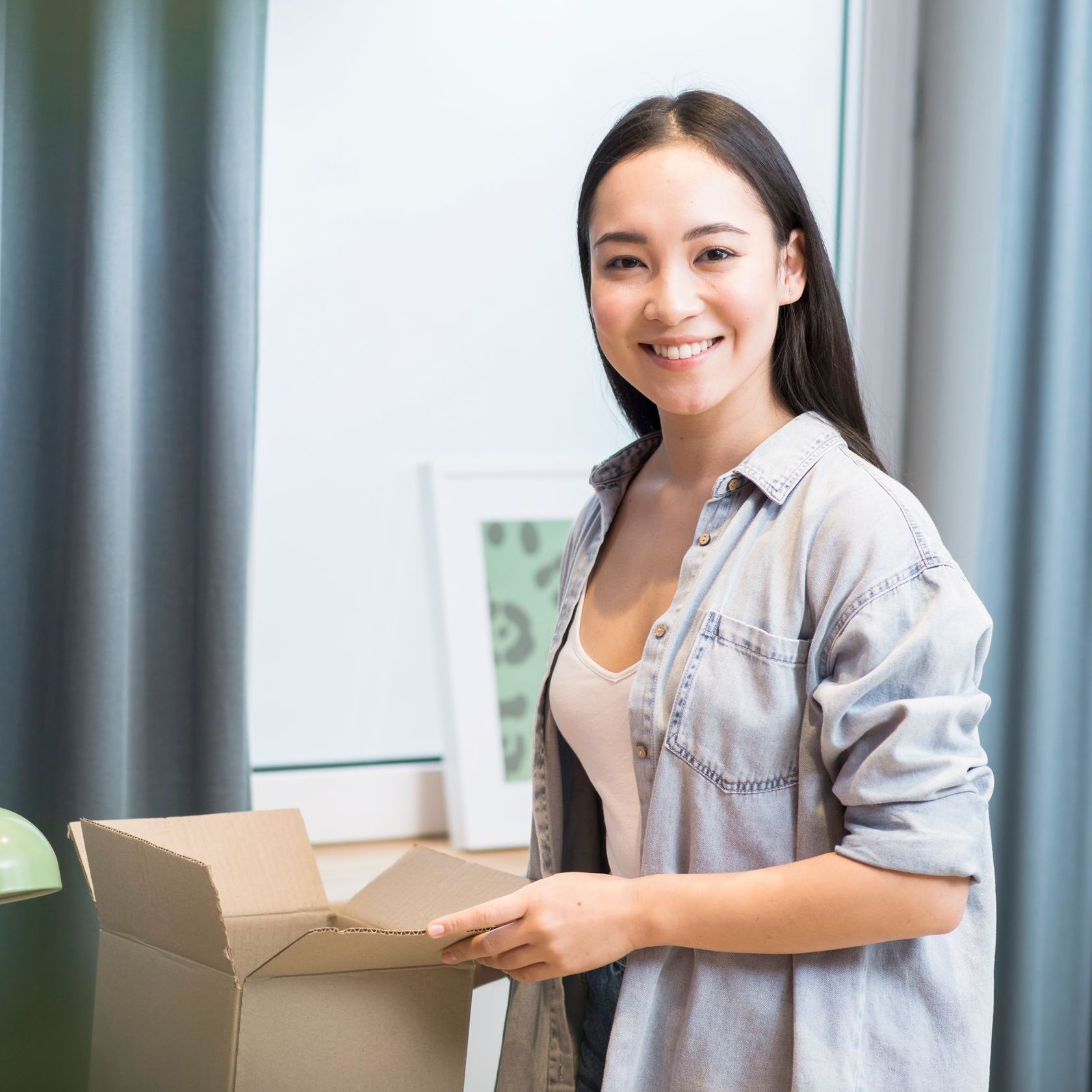 A woman is standing next to a cardboard box and smiling.