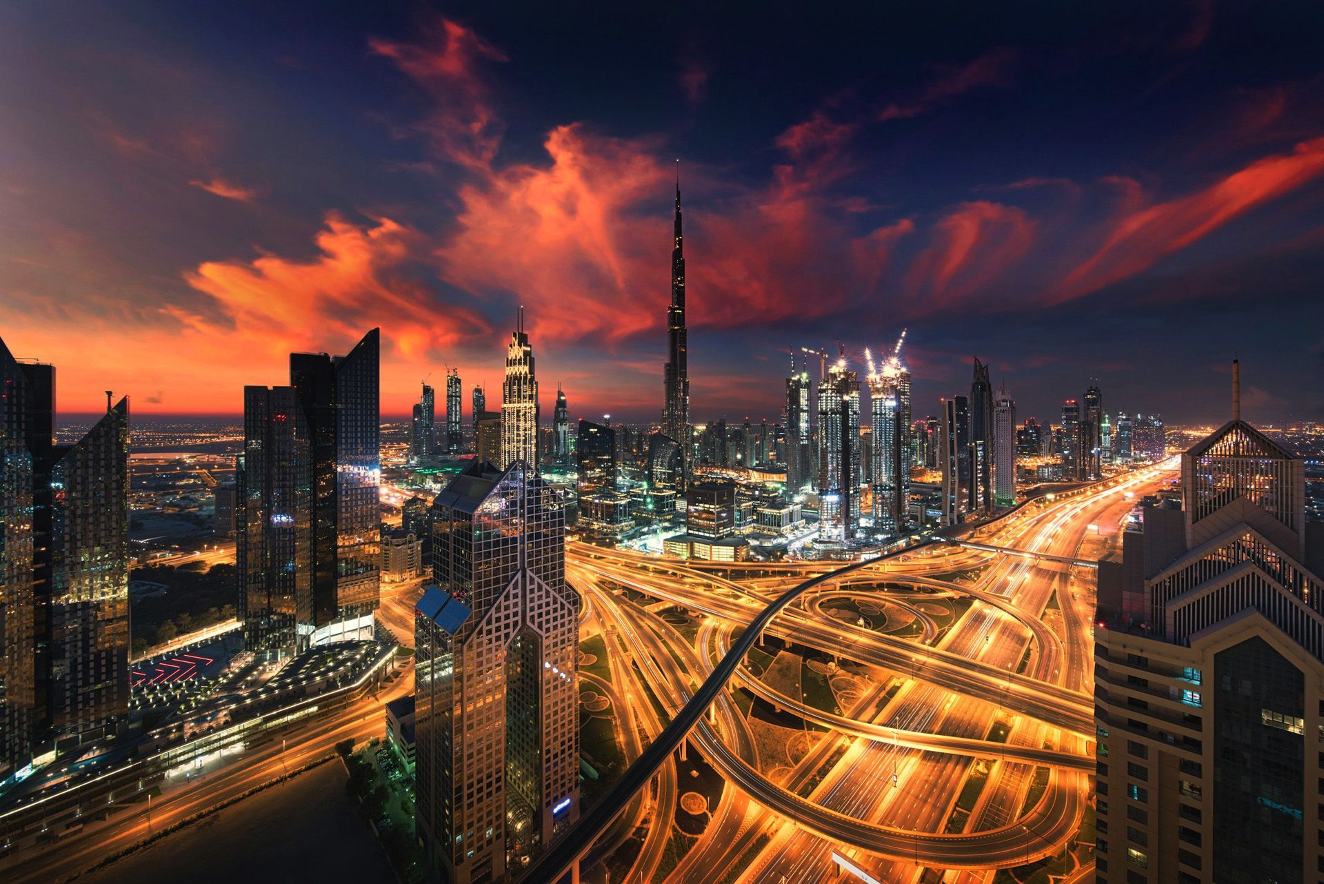 An aerial view of a city at night with a sunset in the background.