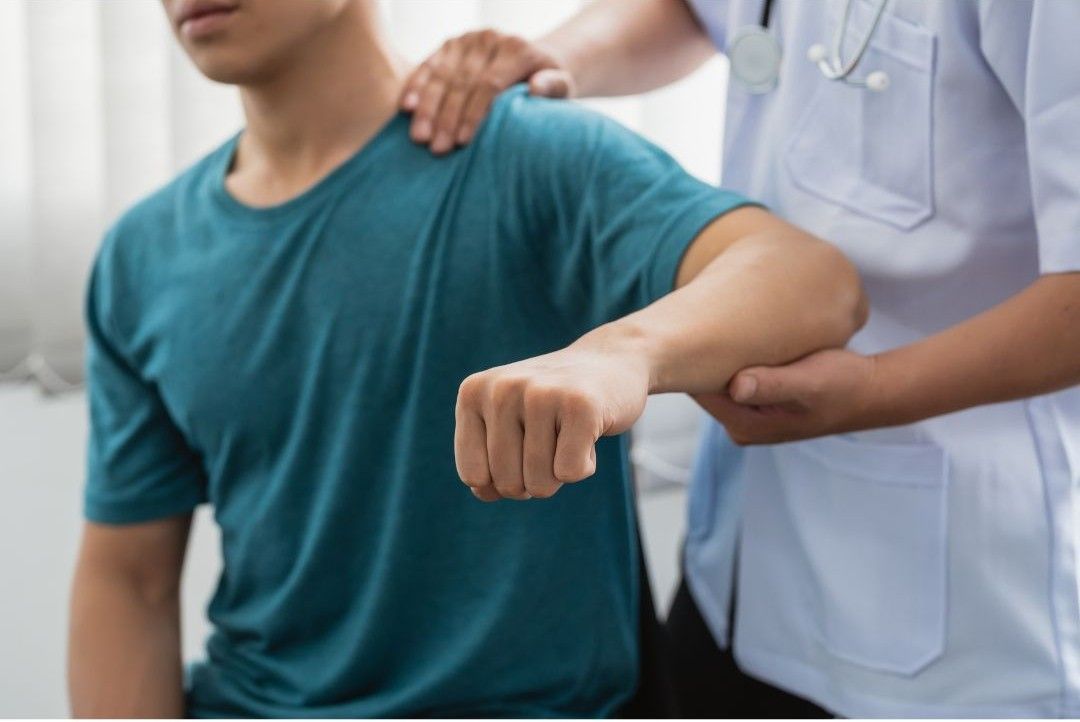 A healthcare professional in a white coat performs a physical assessment of a patient's shoulder.