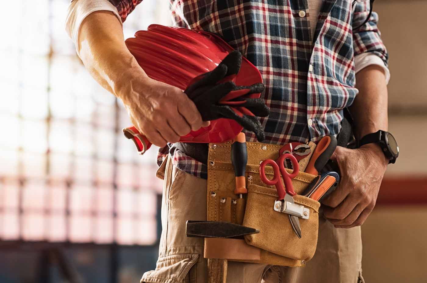 A man is wearing a hard hat and a tool belt.