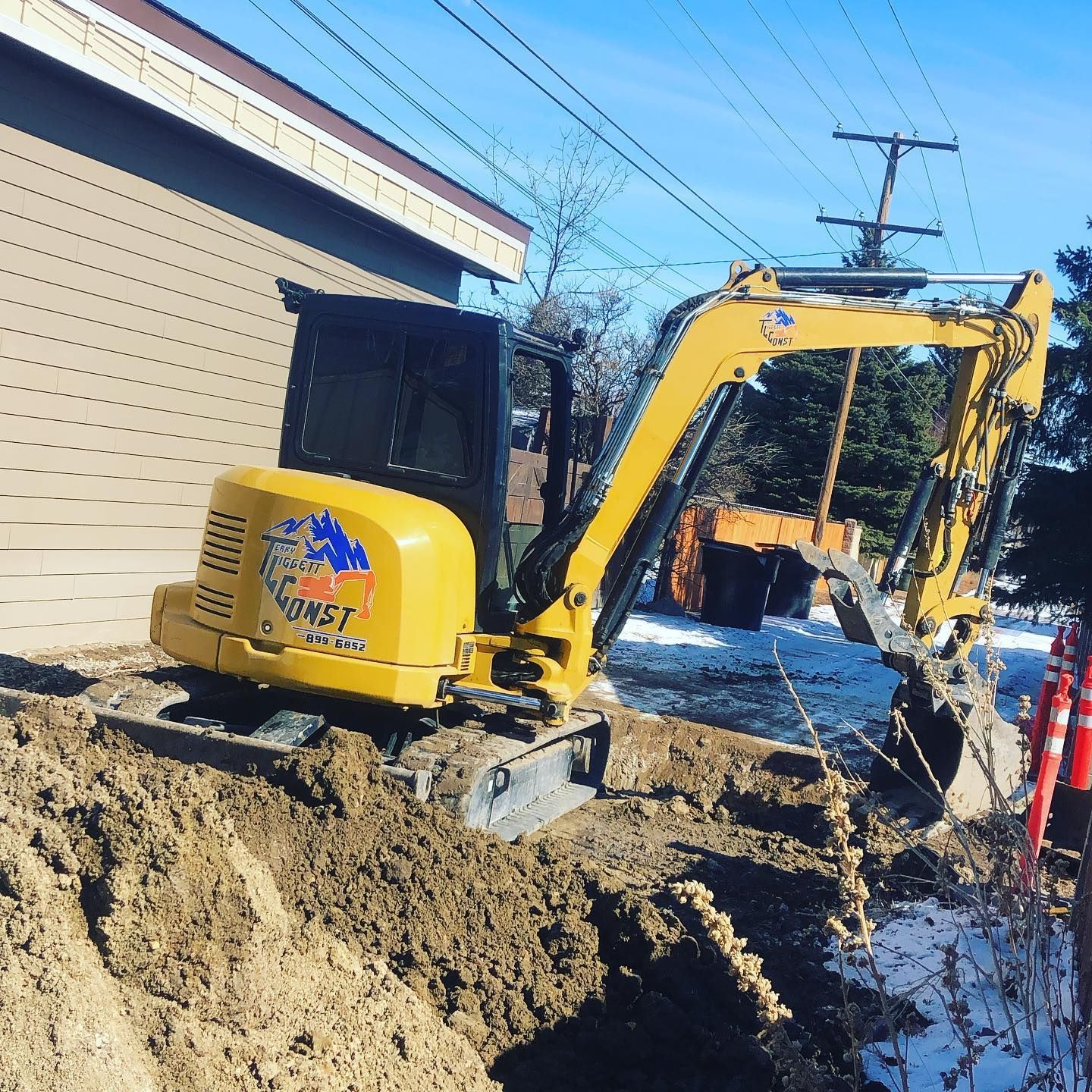 A yellow excavator is digging a hole in the dirt