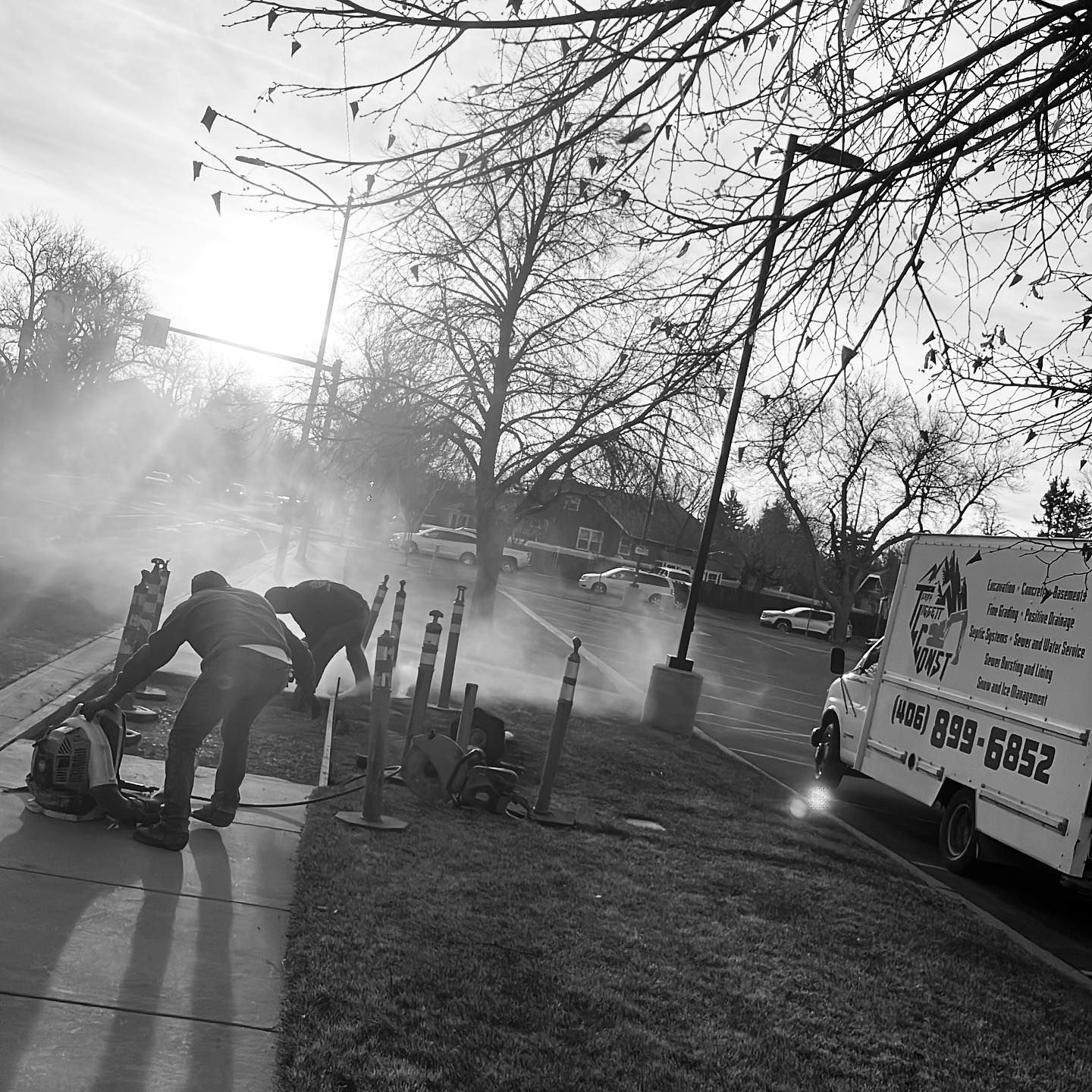 A black and white photo of two men working on a sidewalk next to a white van with the number 4858-6685 on it.