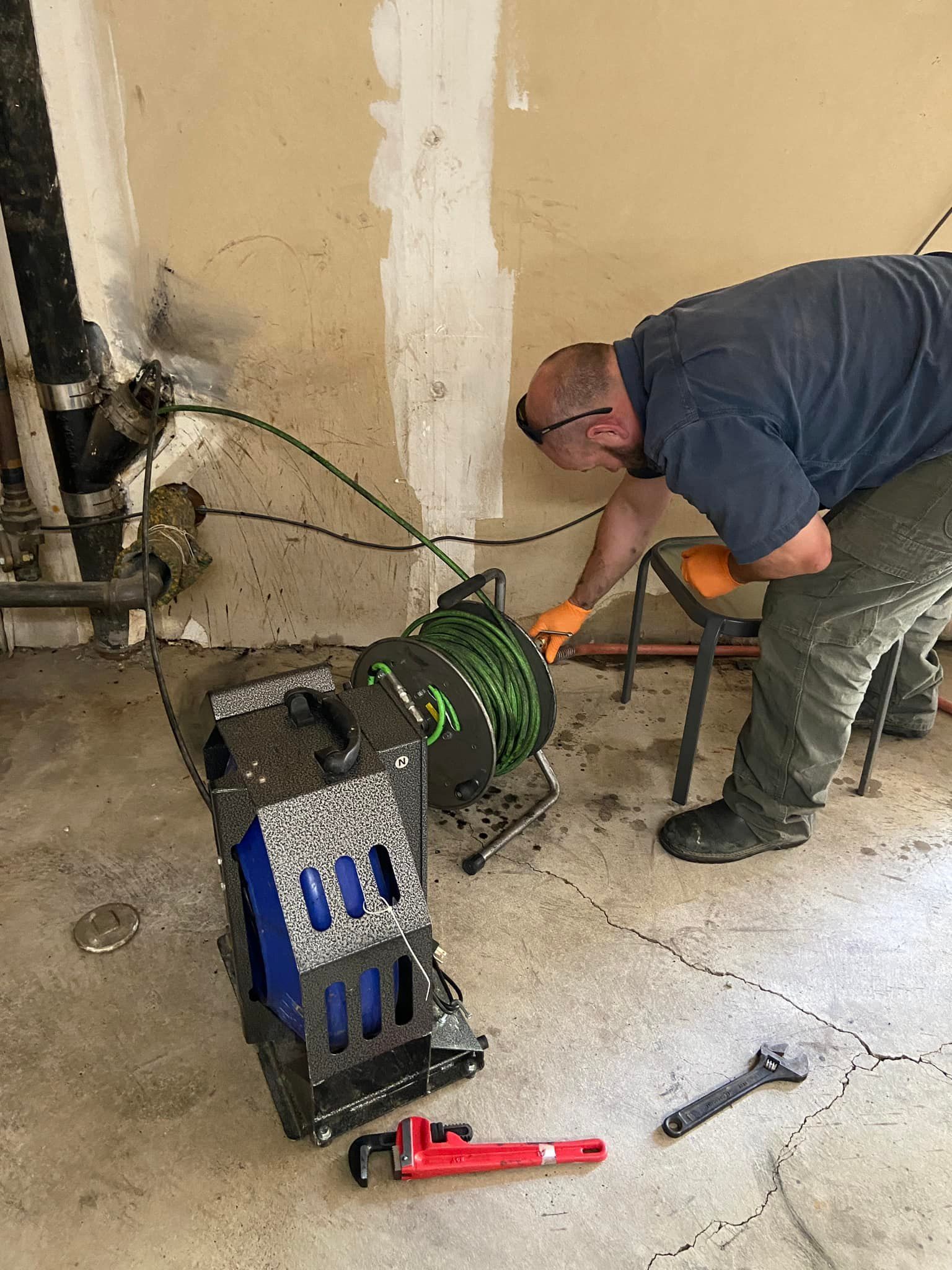 A man is working on a pipe with a hose in a room.