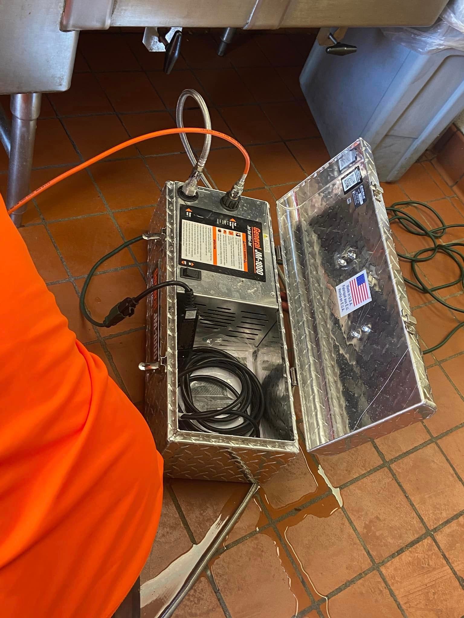 A person is standing next to a metal box with a cord coming out of it.