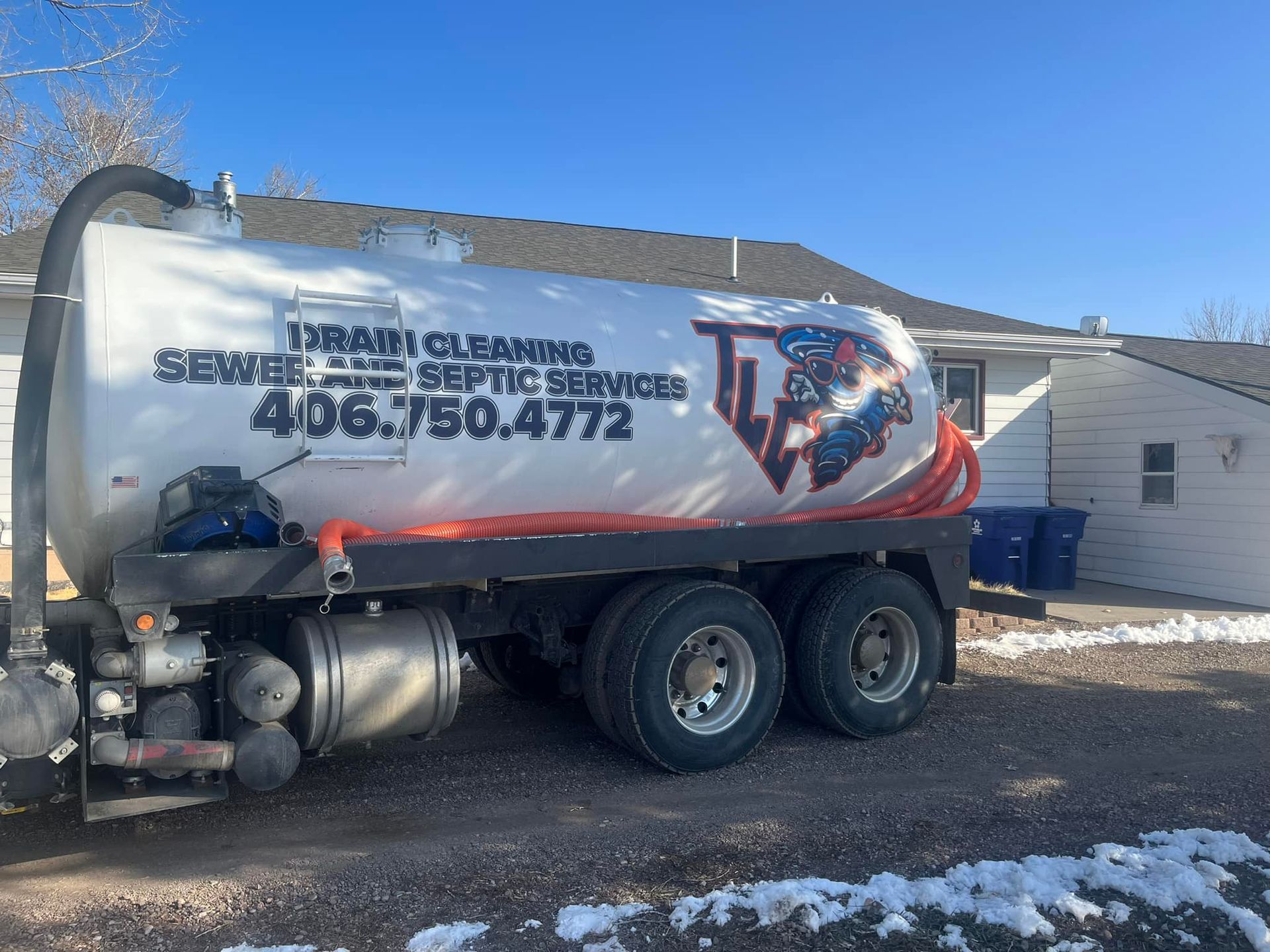 A septic tank truck is parked in front of a house.