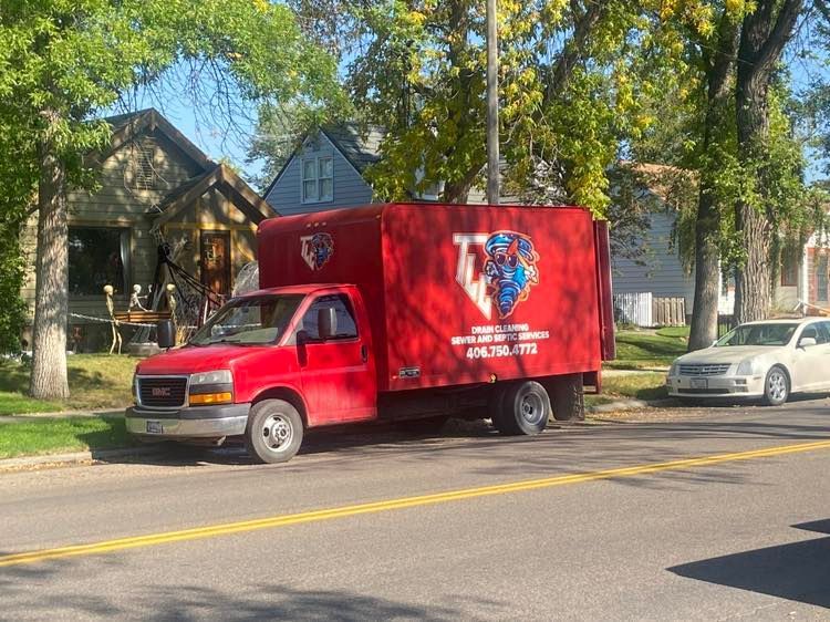 A red truck is parked on the side of the road in front of a house.