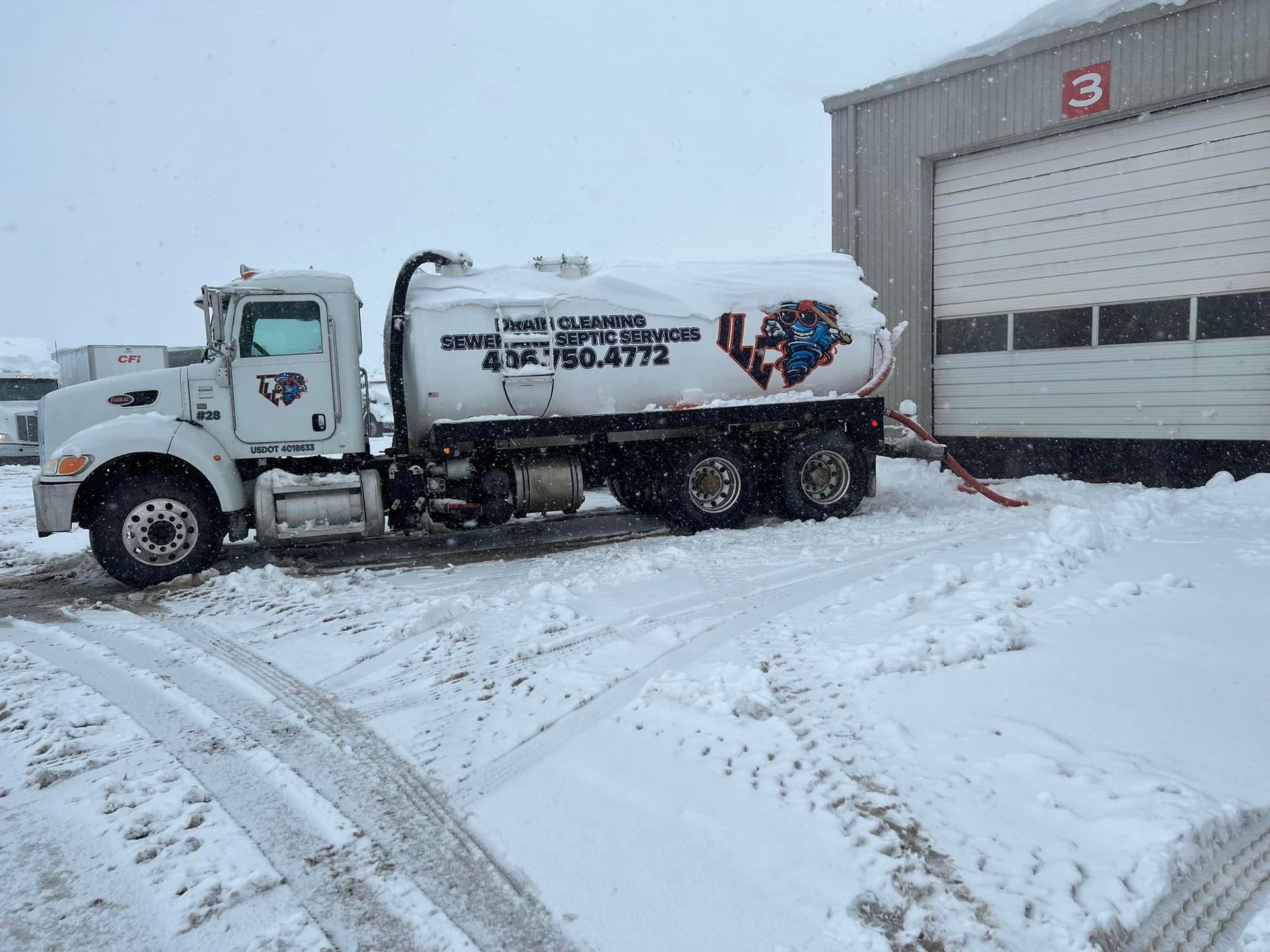 A white truck is parked in the snow in front of a garage.