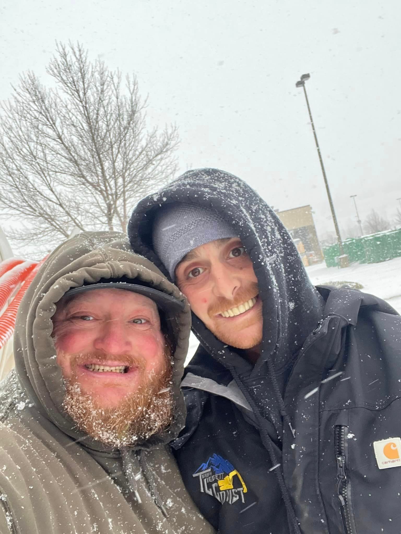 Two men are posing for a picture in the snow.