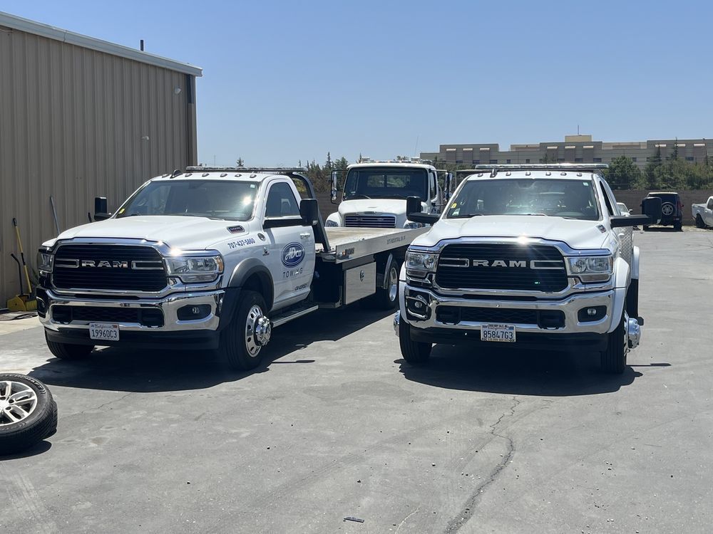 Two white ram tow trucks are parked next to each other in a parking lot.