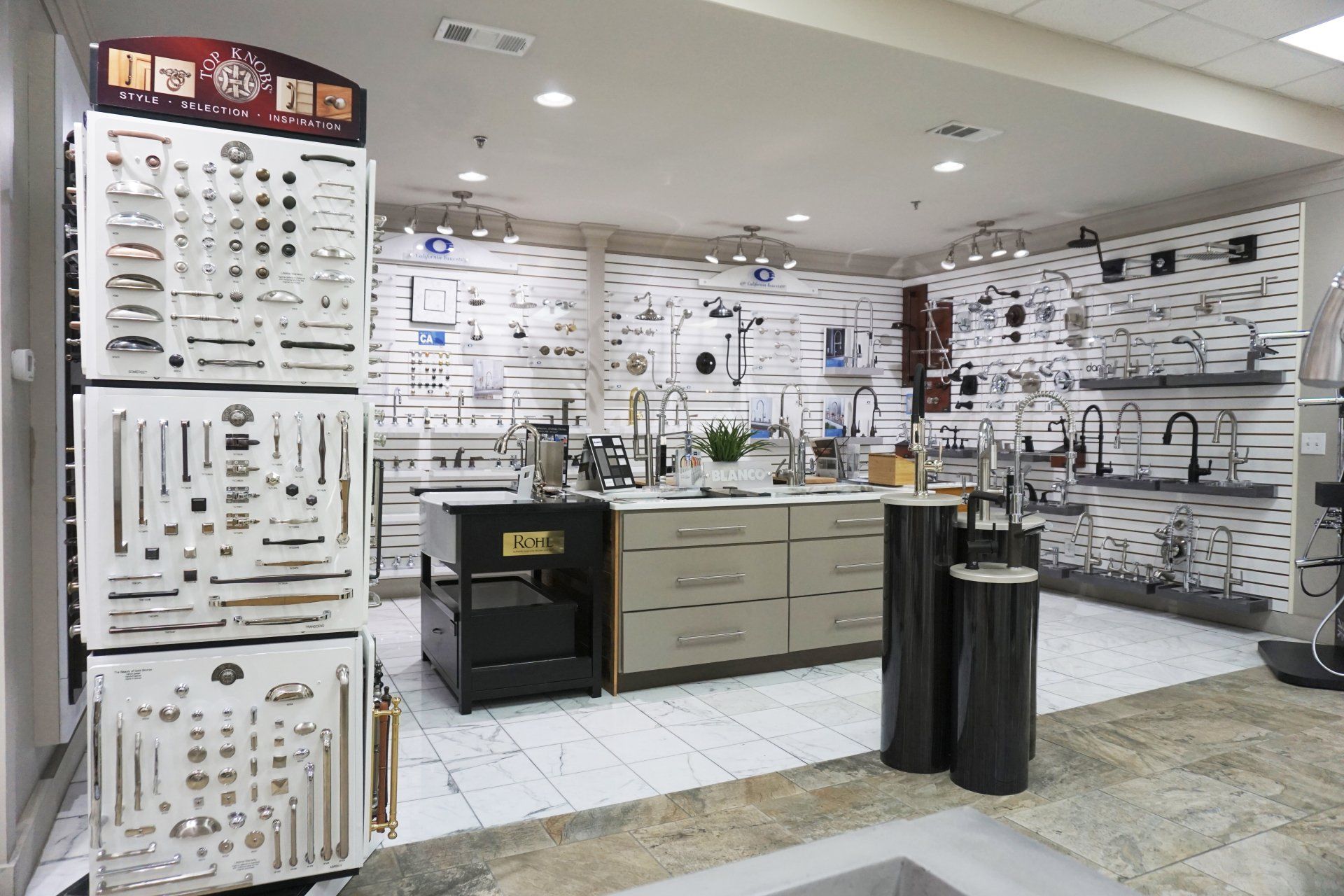 Interior of a hardware store showing cabinet pulls and faucets displayed on white walls and fixtures.