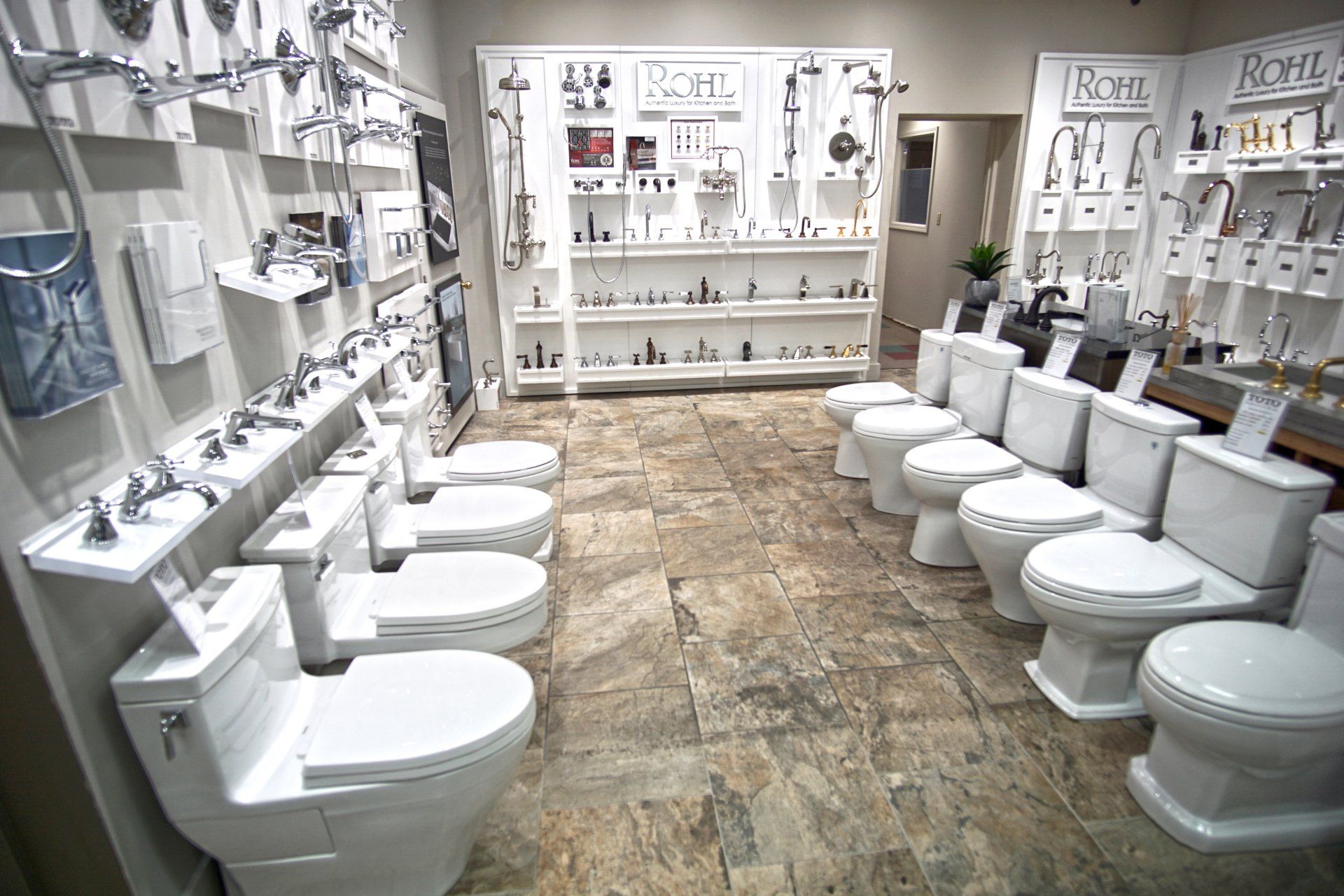 Bathroom showroom with rows of toilets and displays of faucets and showerheads.
