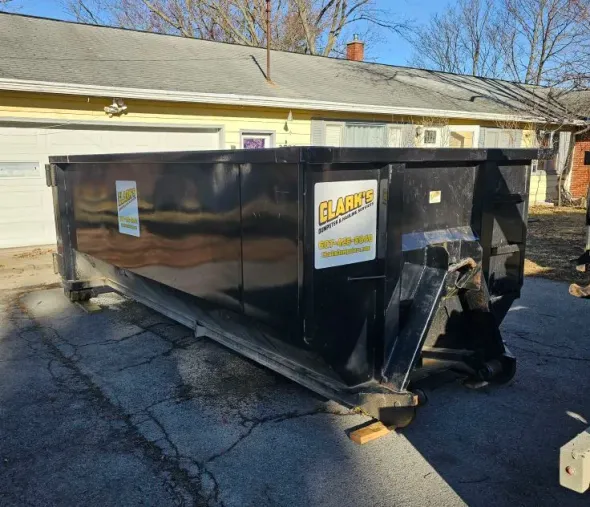 A large yellow dumpster is sitting on the side of a road.