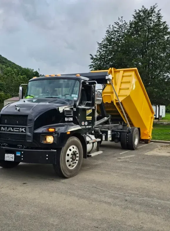 Black Mack truck with a raised yellow dump container.