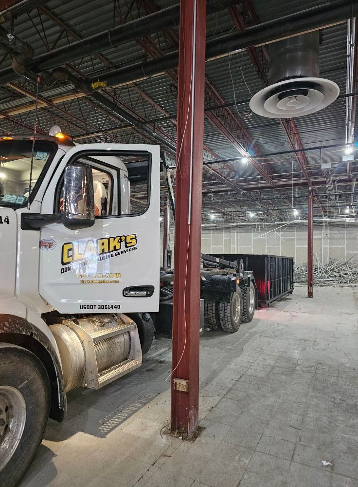 A white Clark's truck with an open door parked inside a large, industrial warehouse space with exposed ceiling beams.