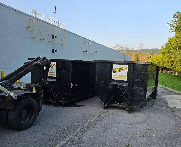 A dumpster truck is parked in front of a building.